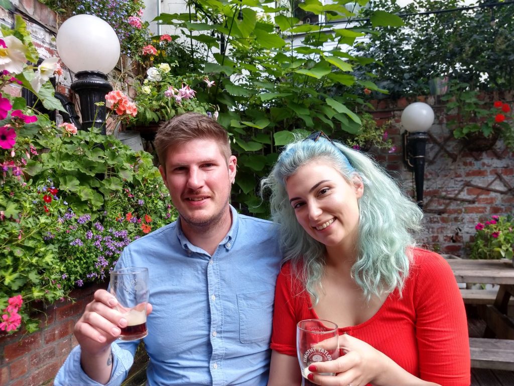 Tour guests with beers in the blooming garden of Duck and Drake